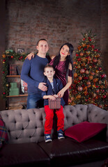 Happy family mom, dad and son with a gift at home at the Christmas tree. Happy New Year and Christmas.