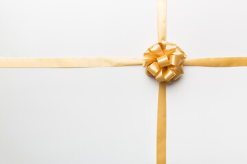 Fototapeta premium Top view of gold ribbon rolled and yellowbow isolated on colored background. Flat lay with copy space