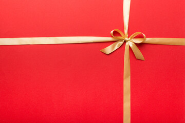 Top view of gold ribbon rolled and yellowbow isolated on colored background. Flat lay with copy...