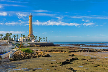 lighthouse on the beach in Chipiona during low tide on the shore are old fishing corrals