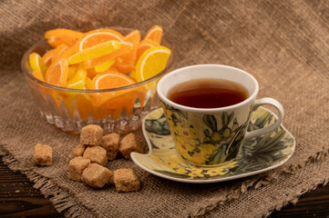Multicolored shaped marmalade lemon slices in a glass vase, pieces of brown cane sugar and a cup of...