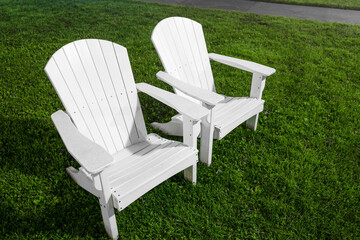 Two white Cape Cod Adirondack chairs on the green