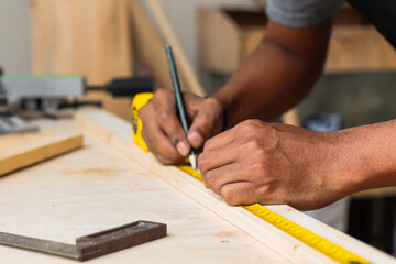 Hand of carpenter working on workshop table using measuring tools