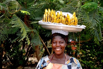 An African Woman Carries A Tray Of Bananas On Her Head