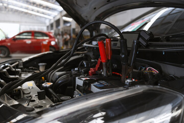 car repair concept. closeup charging car battery with electricity through jumper cables with soft-focus and over light in the background