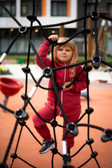 Little girl 5 years old blonde in red clothes plays on the playground © Elena Tcykina