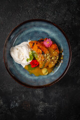 Grilled pumpkin steak in a blue plate on a dark table