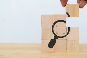 Identify and clarify concept. Market and customer target and focusing. Hand hold the wooden cubes with magnifying glass and cropped object symbols on white background with copy space. - obrazy, fototapety, plakaty
