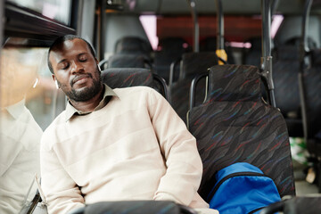Portrait of African-American man sleeping on bus while traveling by public transport in city, copy space