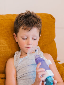Ill child breathing in respirator with inhaler