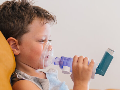 Ill child breathing in respirator with inhaler