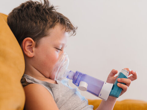 Ill child breathing in respirator with inhaler
