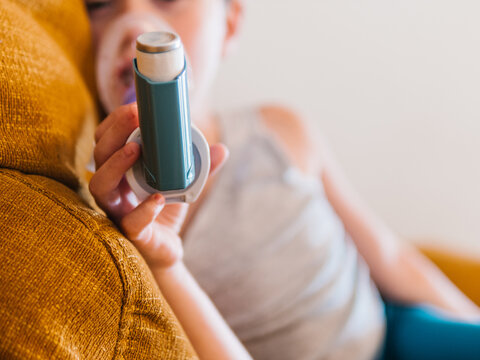 Ill child breathing in respirator with inhaler