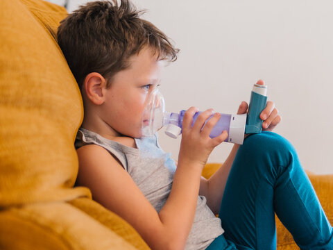 Ill child breathing in respirator with inhaler