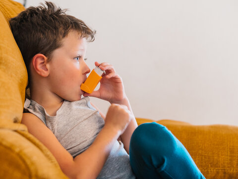 Ill child breathing in respirator with inhaler