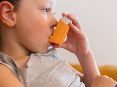 Ill child breathing in respirator with inhaler