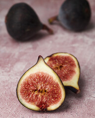 Fresh fig sliced in half with two whole figs in background  isolated on textured background