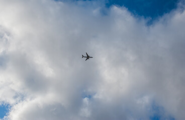 Fototapeta na wymiar A plane is flying high in the blue sky
