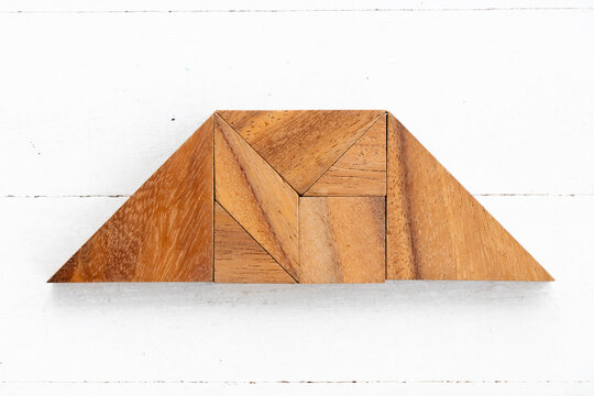 Wood tangram puzzle in trapezium shape on white wood background