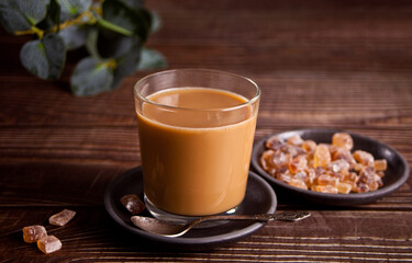 Glass of milky coffee with rock candy sugar.