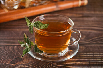 Cup of herbal mint tea with dry herbs on the tray.