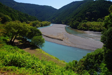 A clear stream flowing between mountains with a large sandbar