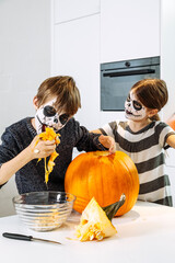 Kids with skull face paint carving a pumpkin