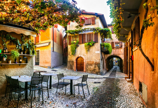 Fototapeta Charming old narrown streets of Italian villages. Malcesine, Garda lake, Italy. Autumn colors, cosy street bars
