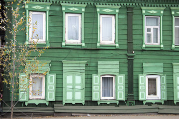 Wooden architecture of Siberia, old Windows with wooden carved architraves. old peeling paint on the wooden Windows - obrazy, fototapety, plakaty