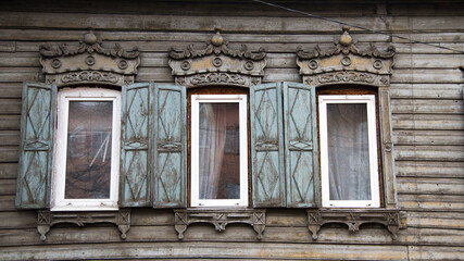 Wooden architecture of Siberia, old Windows with wooden carved architraves. old peeling paint on the wooden Windows