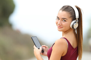 Happy teen looking at you listening to music