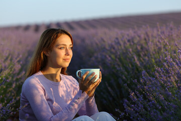 Woman sitting at sunset drinking in lavender field