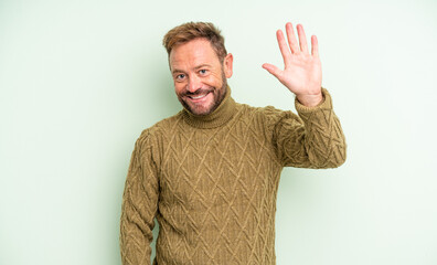 middle age handsome man smiling happily and cheerfully, waving hand, welcoming and greeting you, or saying goodbye © kues1