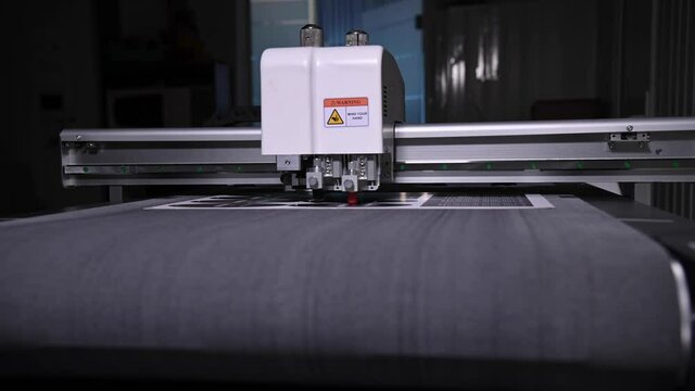 An industrial advertising plotter close-up cuts a template on the cardboard packaging for products. shallow depth of field in real time. Live camera
