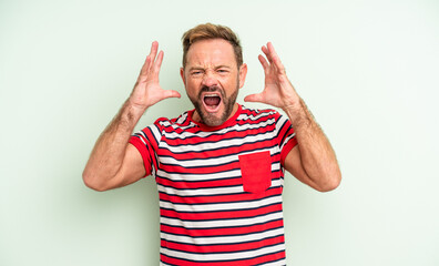 middle age handsome man screaming with hands up in the air, feeling furious, frustrated, stressed...