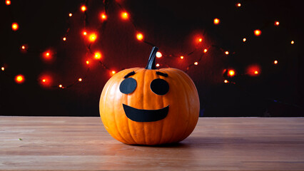 Jack O'Lantern orange pumpkin smiling happily on a wooden table. Copy space available at each side.