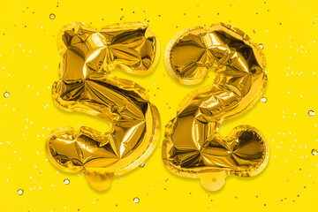 The number of the balloon made of golden foil, the number fifty-two on a yellow background with...