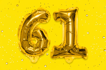 The number of the balloon made of golden foil, the number sixty-one on a yellow background with...