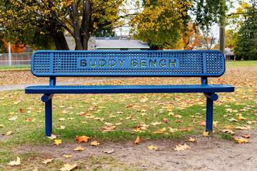 Blue buddy bench in park in autumn season at schoolyard
