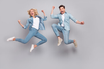 Fototapeta na wymiar Full size photo of hooray couple jump wear jeans shirt shoes isolated on grey color background
