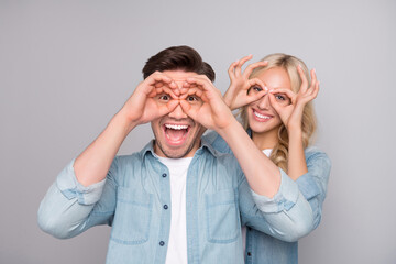 Photo of young cheerful couple happy positive smile finger binoculars childish playful isolated over grey color background