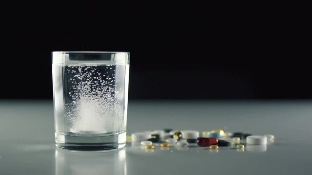 Pill falling down in glass with water and make acidity bubble.