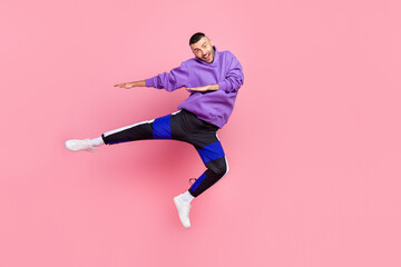 Fototapeta na wymiar Full body photo of nice young brunet guy jump wear hoodie pants shoes isolated on pink background