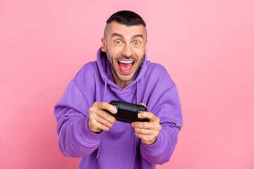 Photo of young addicted crazy man play console game joystick race isolated over pink color...