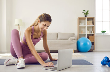 Young woman at home during morning sports workout turns on online workout video on her laptop....