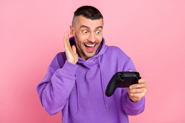 Photo of impressed millennial brunet guy look playstation wear violet hoodie isolated on pink background © deagreez