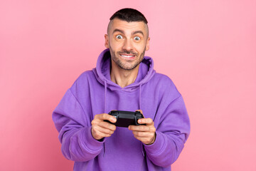 Photo of cute young brunet guy playstation wear violet hoodie isolated on pink background