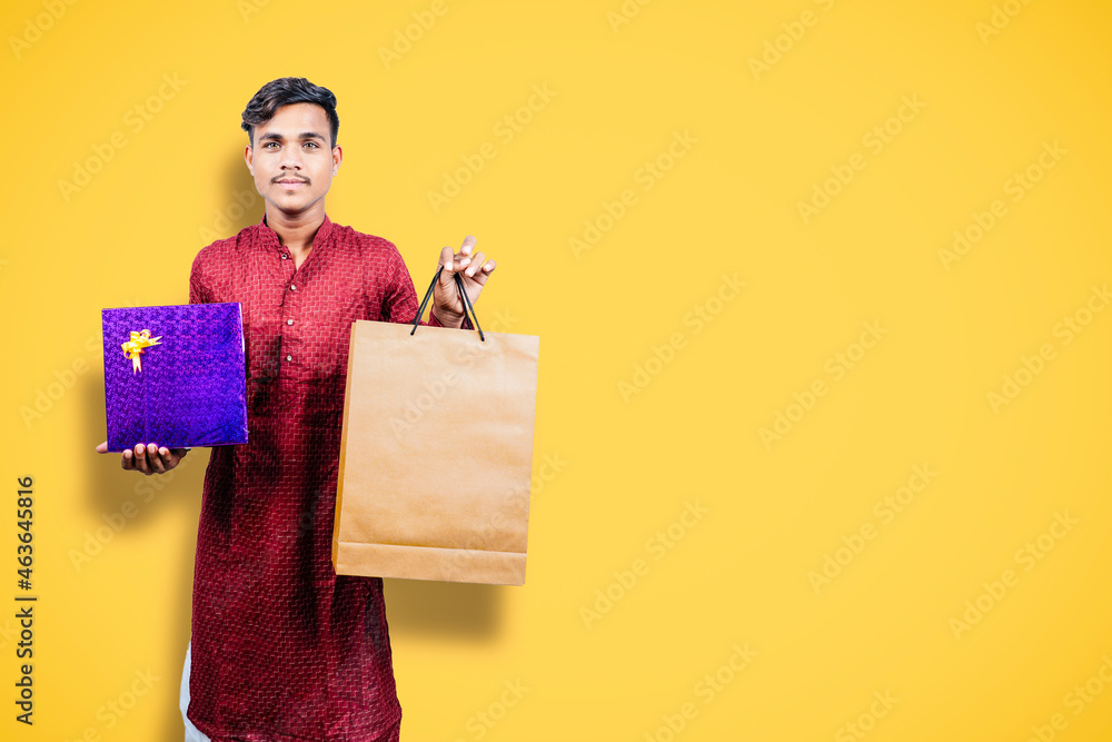 Wall mural Indian man in ethnic wear with shopping bags, isolated over yellow background