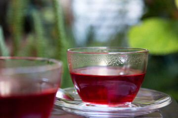Glass cups of hot red hibiscus tea on a wooden tray at terrace. Close up
