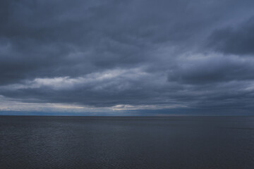 Fototapeta na wymiar Blue dark evening sky with clouds and dark sea background